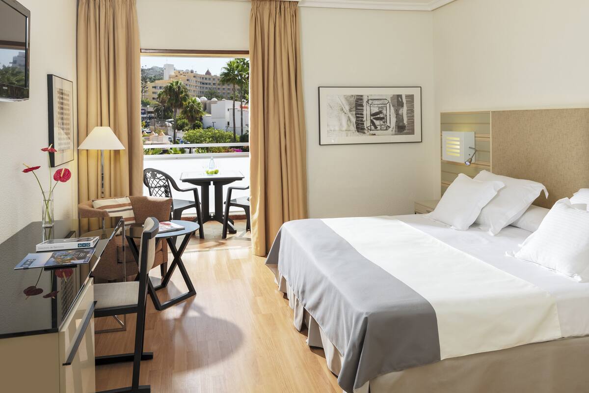 Habitación de hotel con cama, escritorio, silla y vistas a la ciudad.