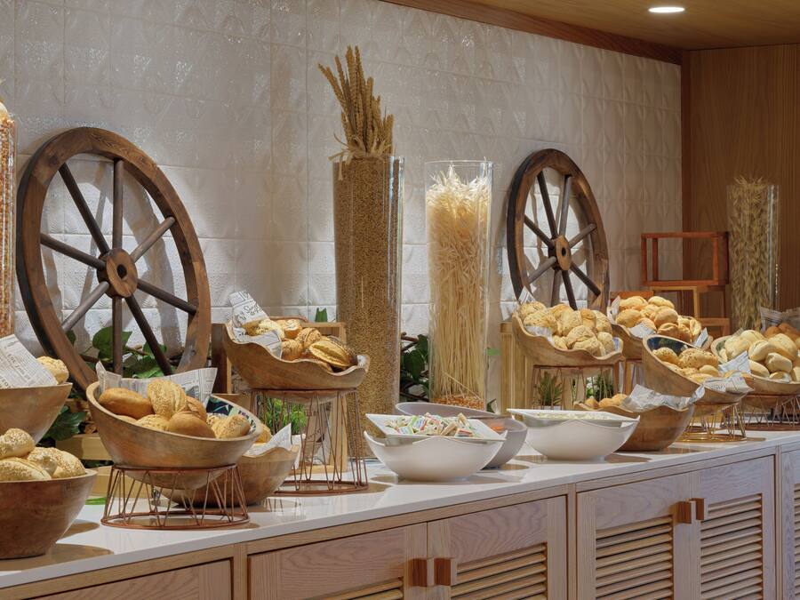 A buffet table with various breads and pastries displayed in wooden bowls and baskets.