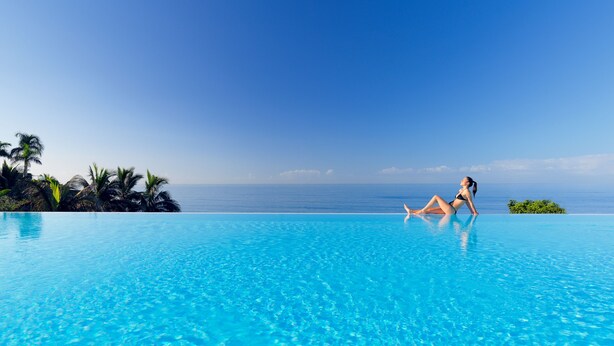 A woman relaxing on a poolside with a clear view of the ocean.