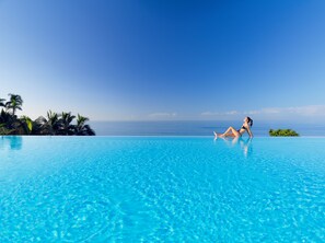 A woman relaxing on a poolside with a clear view of the ocean.