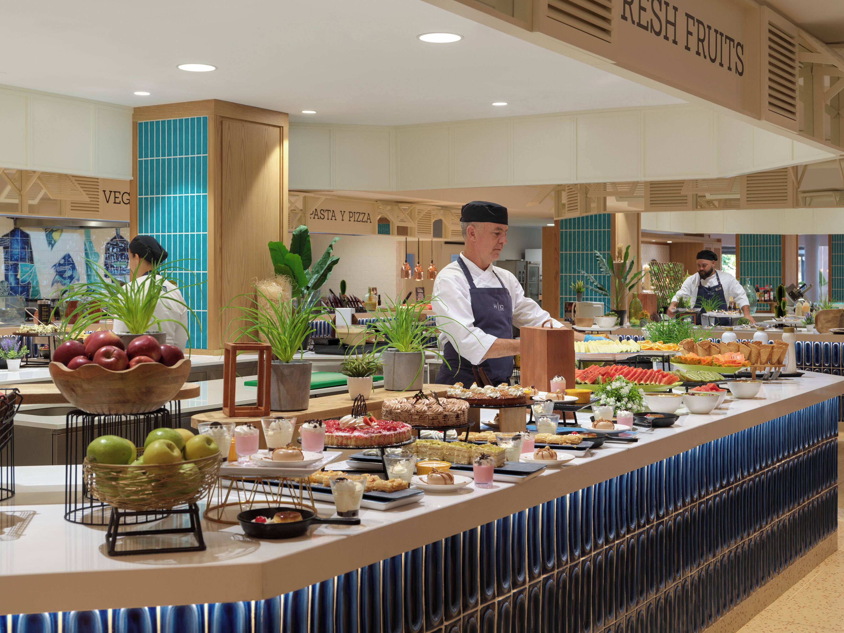 A buffet area with a variety of food items and a staff member serving.