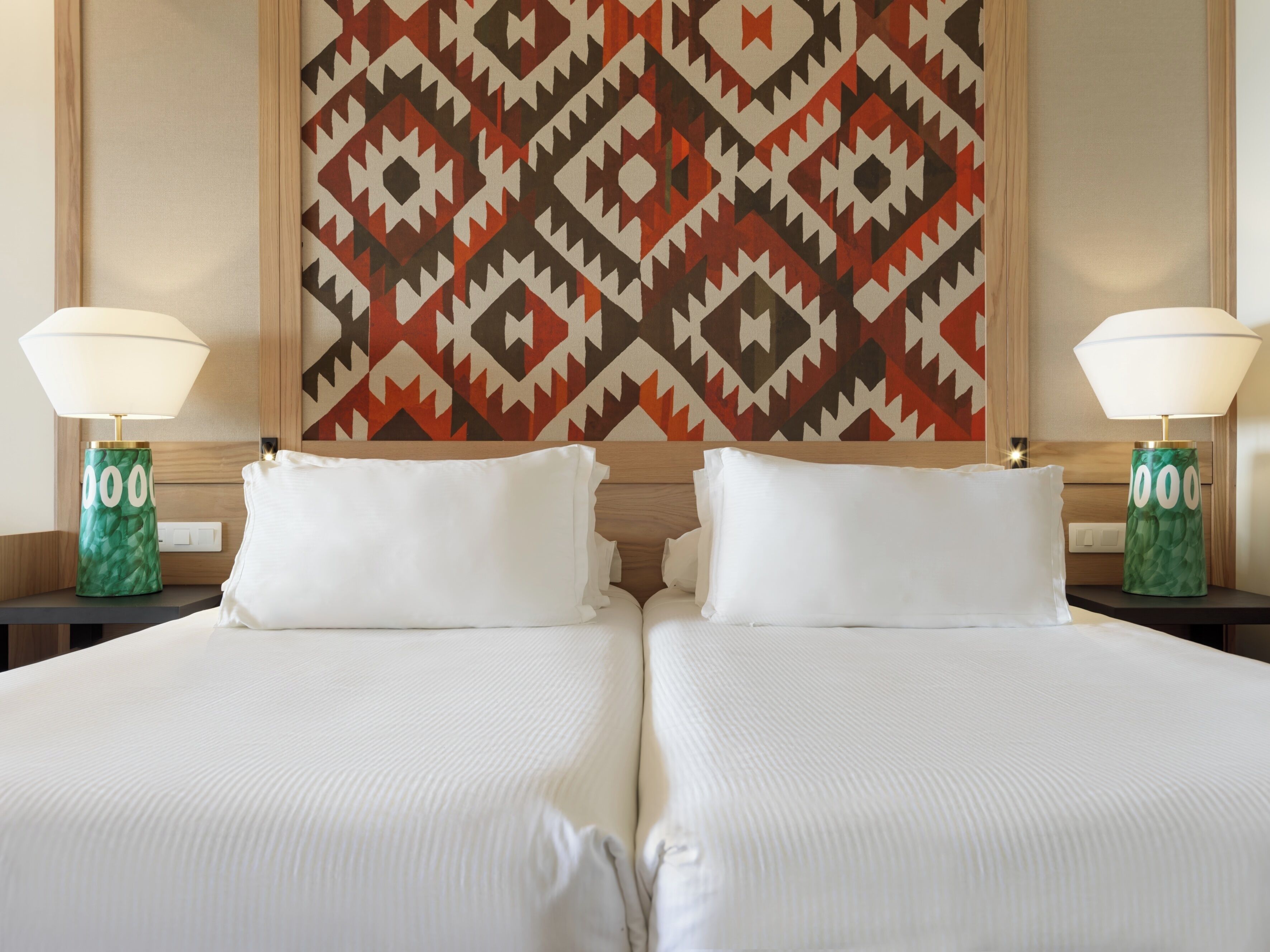 A hotel room with two beds, white linens, and a patterned wall hanging.