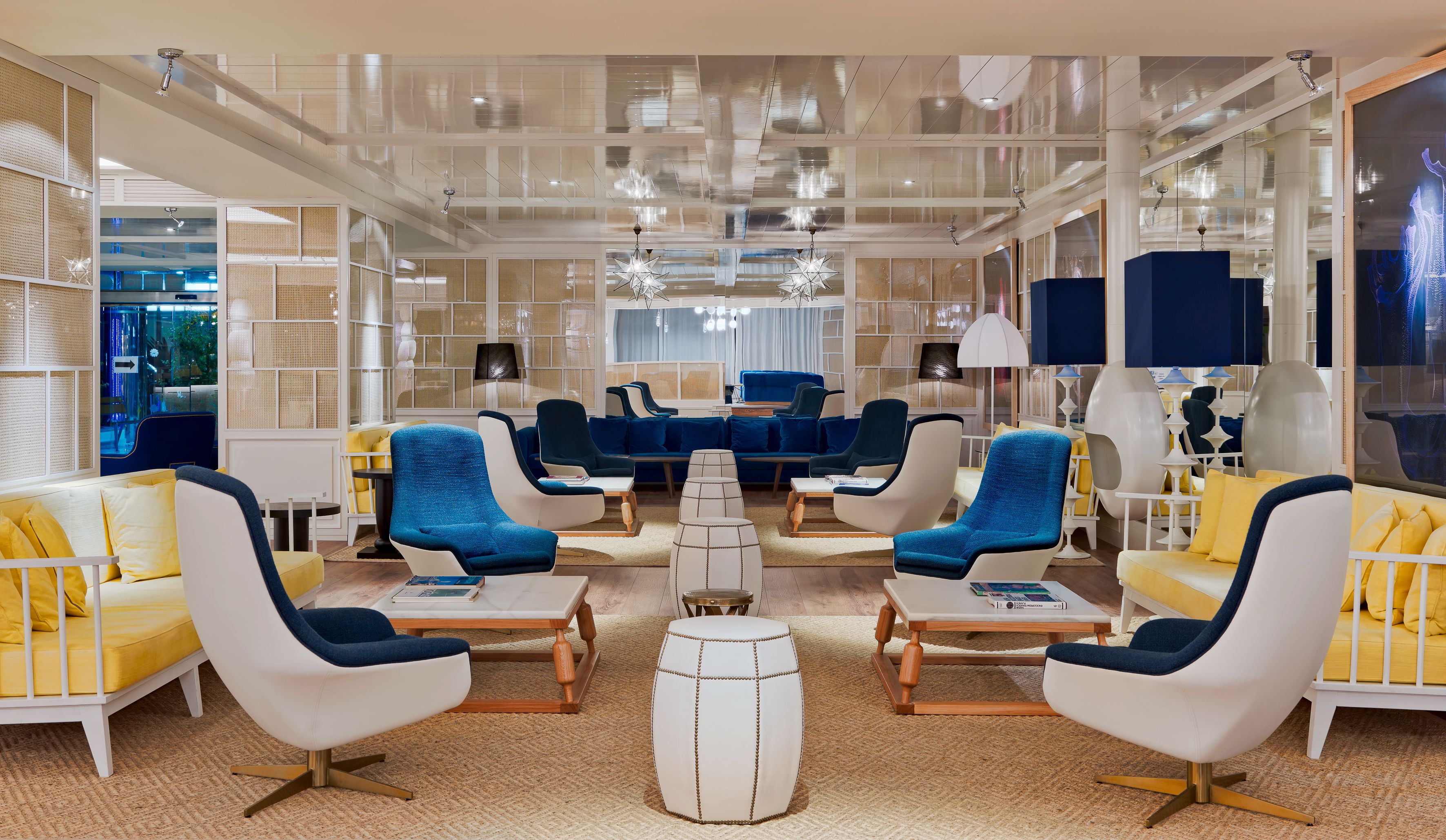 A modern lounge area with seating arrangements, a central coffee table, and a large window providing natural light.