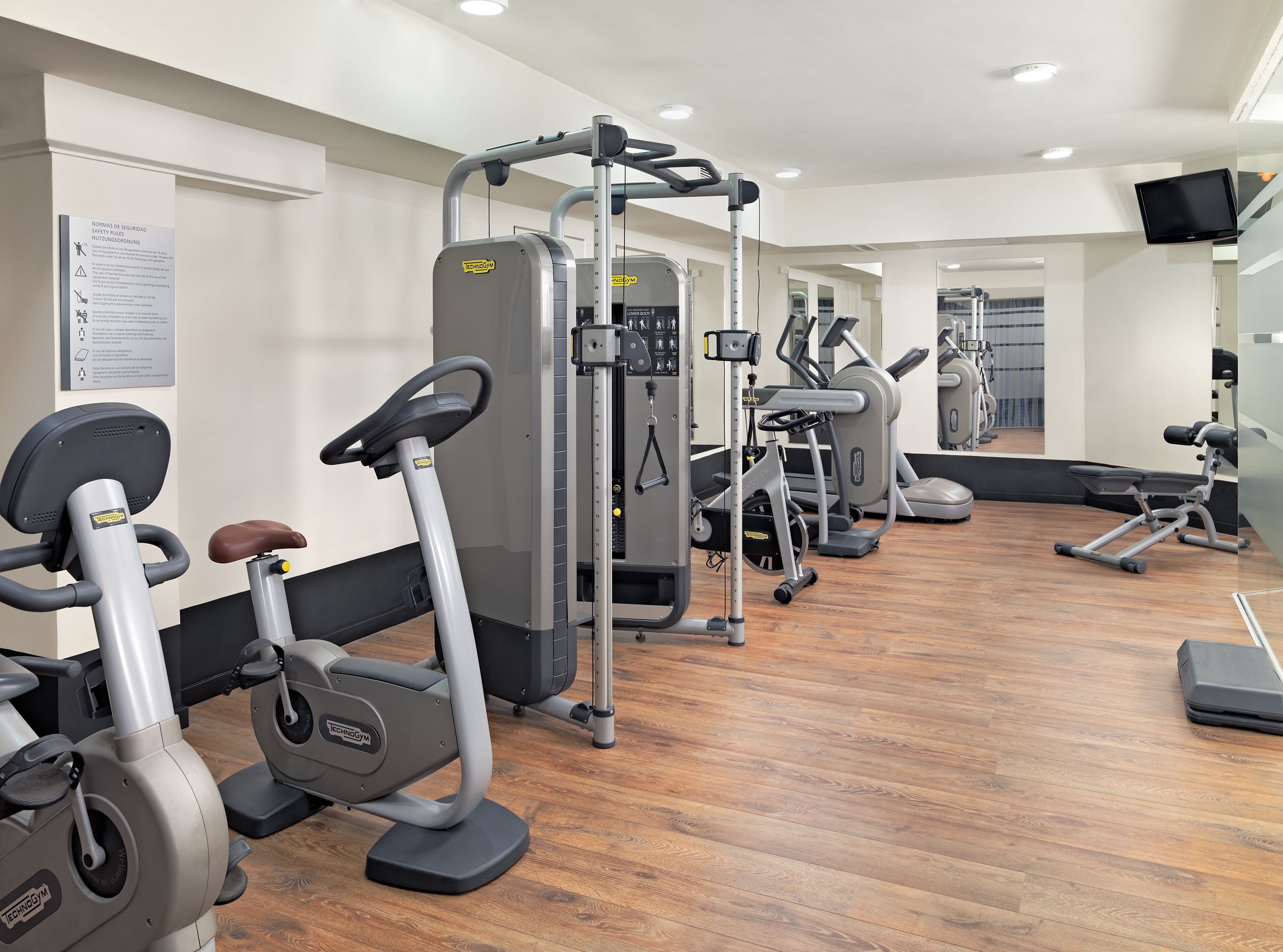 Ein Fitnessraum mit Cardiogeräten, Gewichtsmaschinen und einer Spiegelwand.