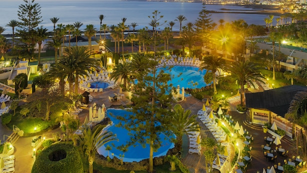 Un resort con varias piscinas, palmeras y vistas al mar.
