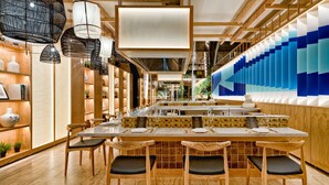 Interior de restaurante moderno con mobiliario de madera, una larga mesa de comedor y una pared con diseño azulado.