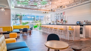 Zona de bar moderna con mostrador, taburetes y un área de estar con sofá y sillas.