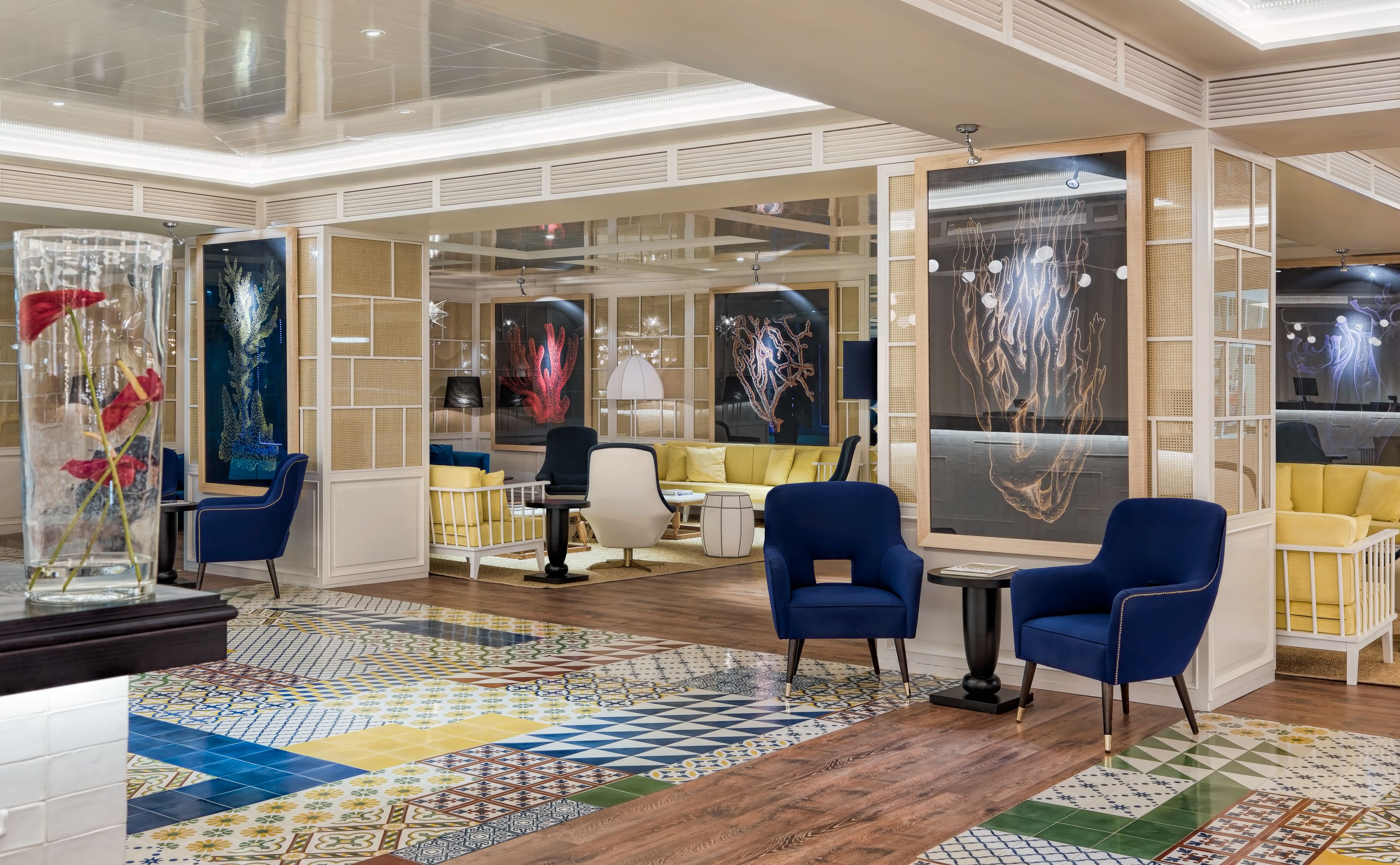 Un interior moderno con piso estampado, sillas azules, sofá amarillo y obras de arte en las paredes.