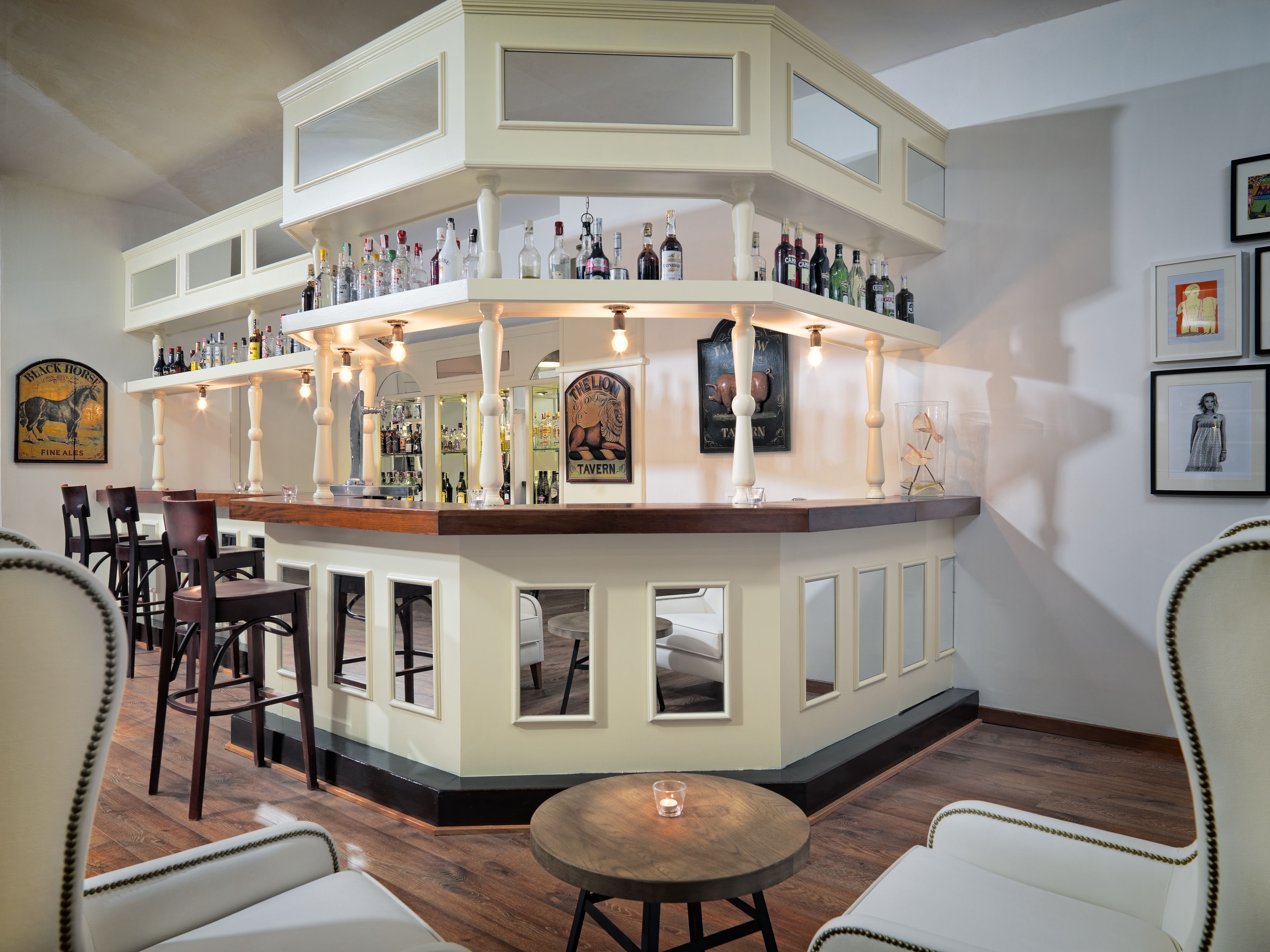 A bar area with multiple shelves of bottles, a counter, and seating with chairs and a table.