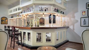 A bar area with multiple shelves of bottles, a counter, and seating with chairs and a table.
