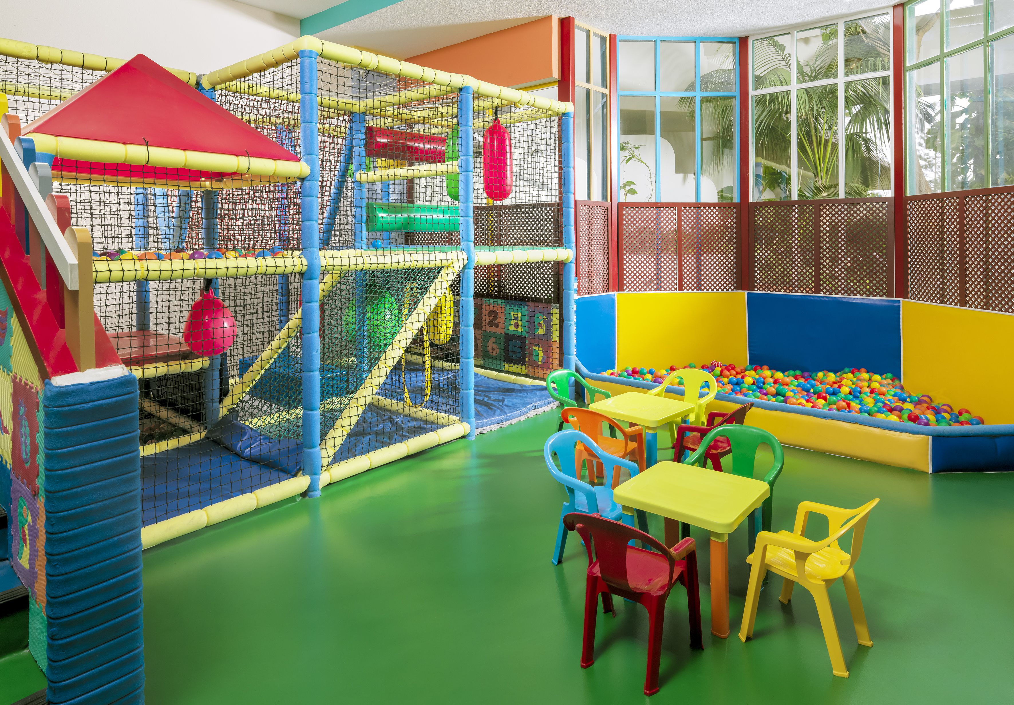 A play area with a climbing net, ball pit, and colorful chairs.