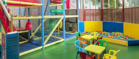 A play area with a climbing net, ball pit, and colorful chairs.