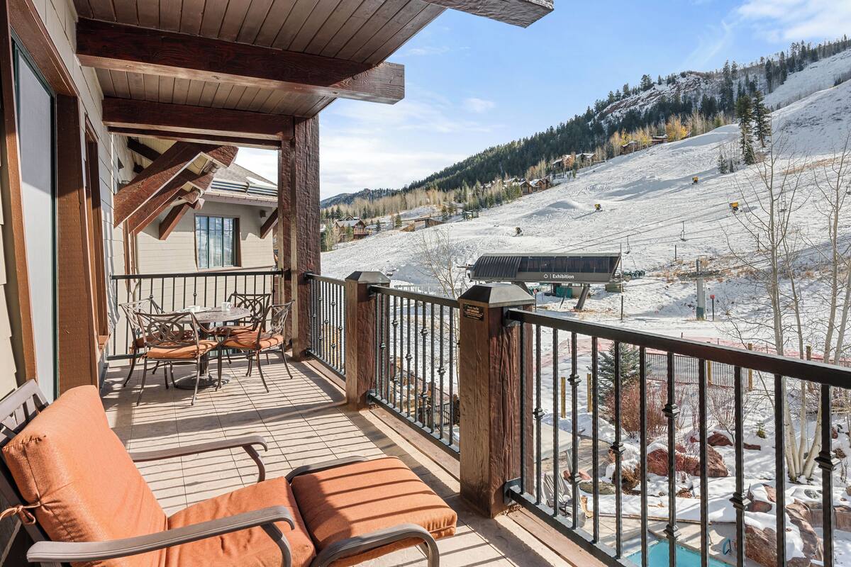 A wooden deck with outdoor seating and a view of a snowy mountain slope.