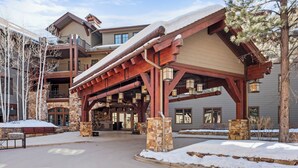A lodge with a covered entrance, stone pillars, and a snow-covered roof. - Ritz-Carlton Club, Aspen Highlands by Frias (Aspen)