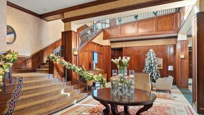 A grand lobby with a staircase, a round table with vases, and a Christmas tree. - Ritz-Carlton Club, Aspen Highlands by Frias (Aspen)