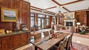 A spacious dining area with a wooden table and chairs, a fireplace, and a bookshelf. - Ritz-Carlton Club, Aspen Highlands by Frias (Aspen)