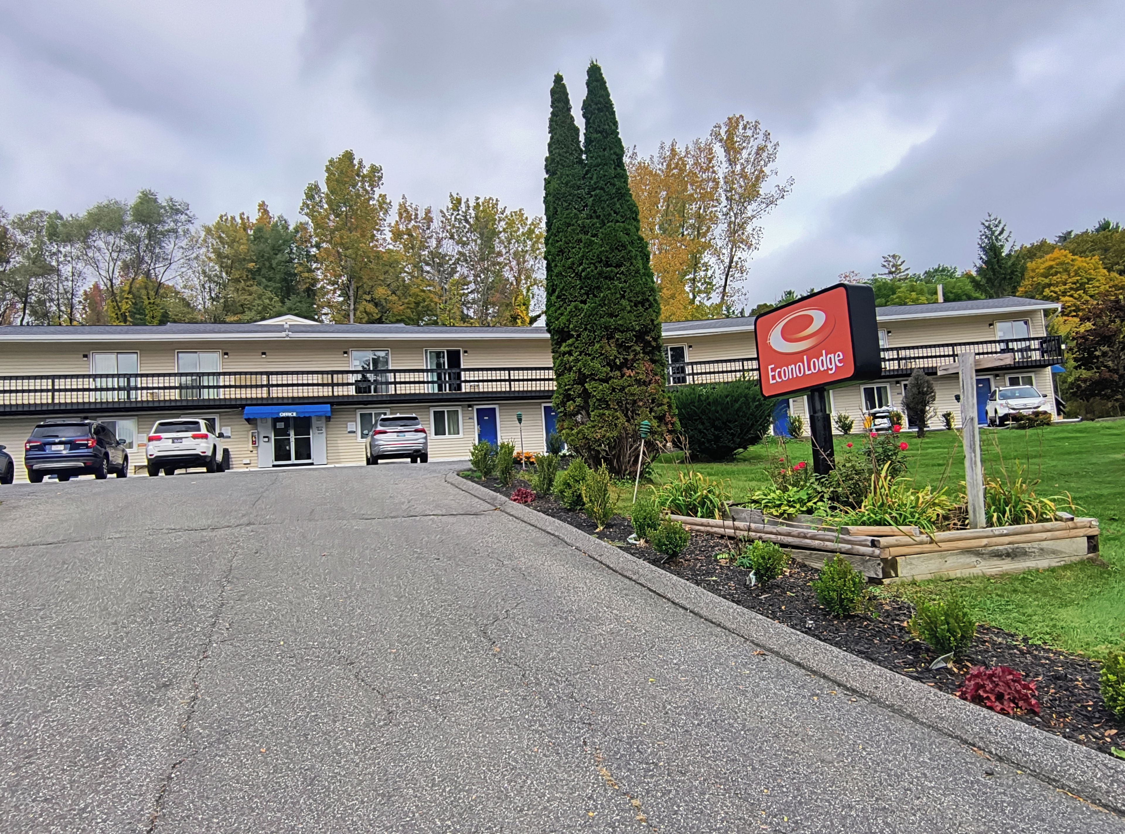 Un motel con estacionamiento, un letrero y un jardín con plantas.