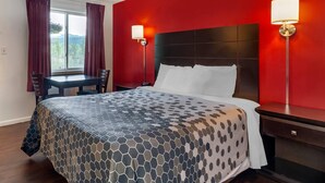 A hotel room with a bed, a desk, and two wall-mounted lamps. - Econo Lodge Lee - Great Barrington (Lee)