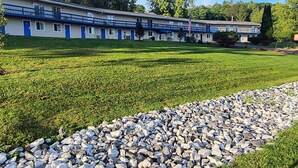 A motel with multiple rooms, a well-maintained lawn, and a stone pathway. - Econo Lodge Lee - Great Barrington (Lee)