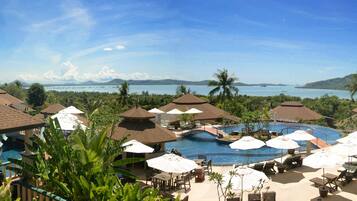 A resort with multiple pools, umbrellas, and a view of the ocean.