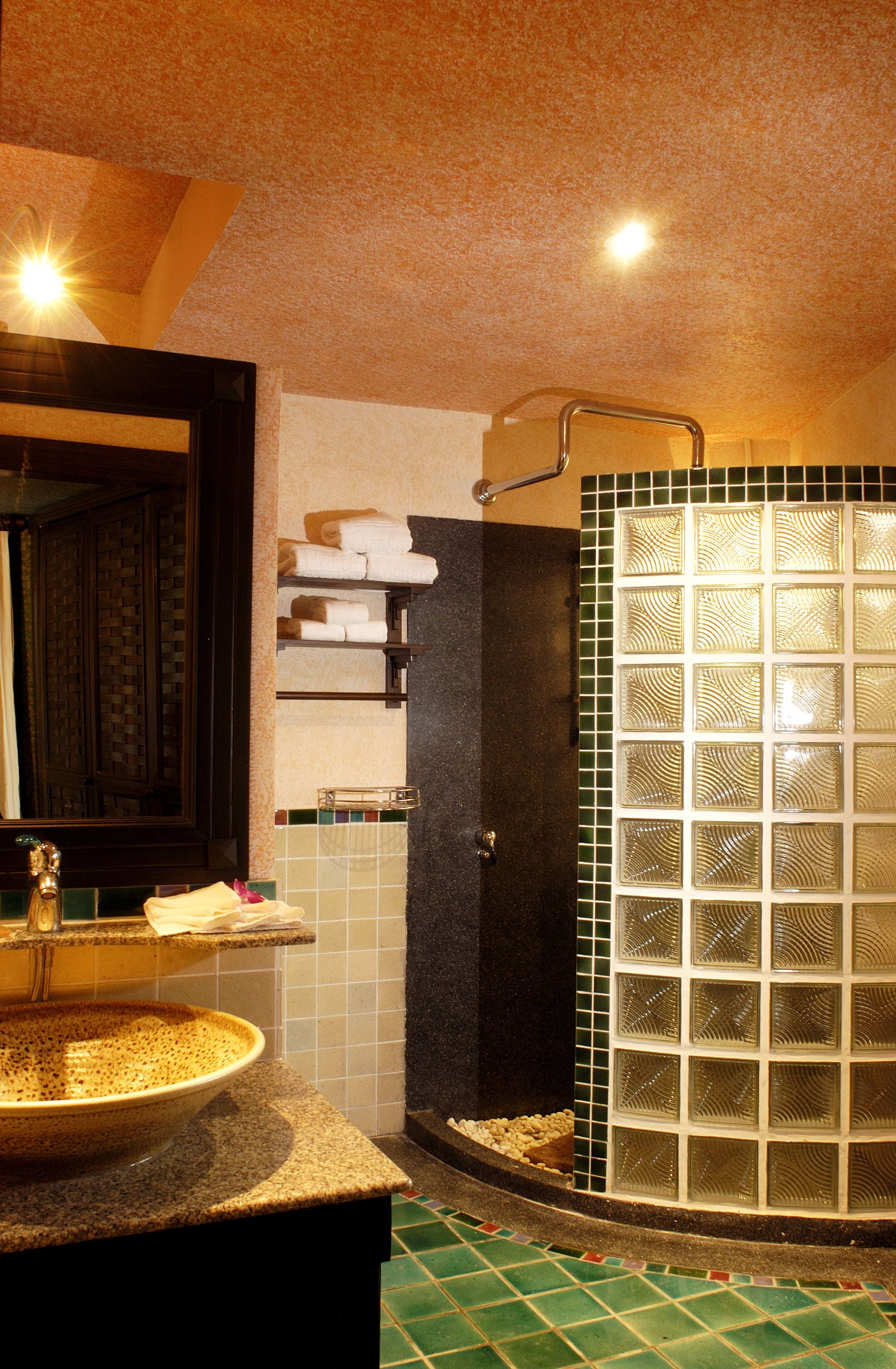 A bathroom with a round sink, a glass shower enclosure, and a tiled floor.