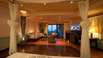 A spacious room with a bed, a sofa, a television, and a view of the outdoors.