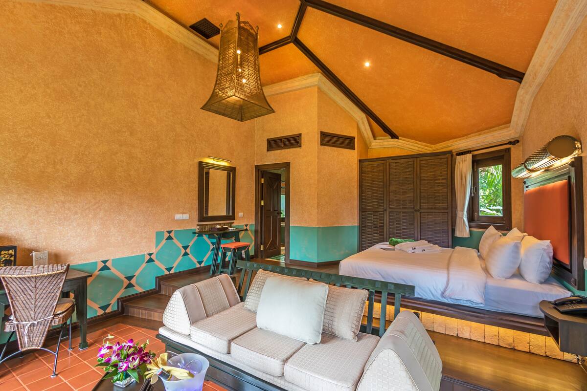 Een hotelkamer met een bed, een bank, een eettafel en een stoel.
