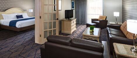 A hotel room with a bed, a TV, a sofa, a coffee table, and a lamp.