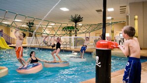 An indoor swimming pool with multiple water slides and a netted climbing structure. - Lake Okoboji Resort & Conference Center (Okoboji)