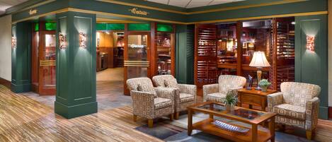 A library with patterned armchairs, a wooden coffee table, and bookshelves.