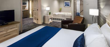 A hotel room with a large bed, a TV, a desk, a chair, a bathroom with a bathtub, and a shower.