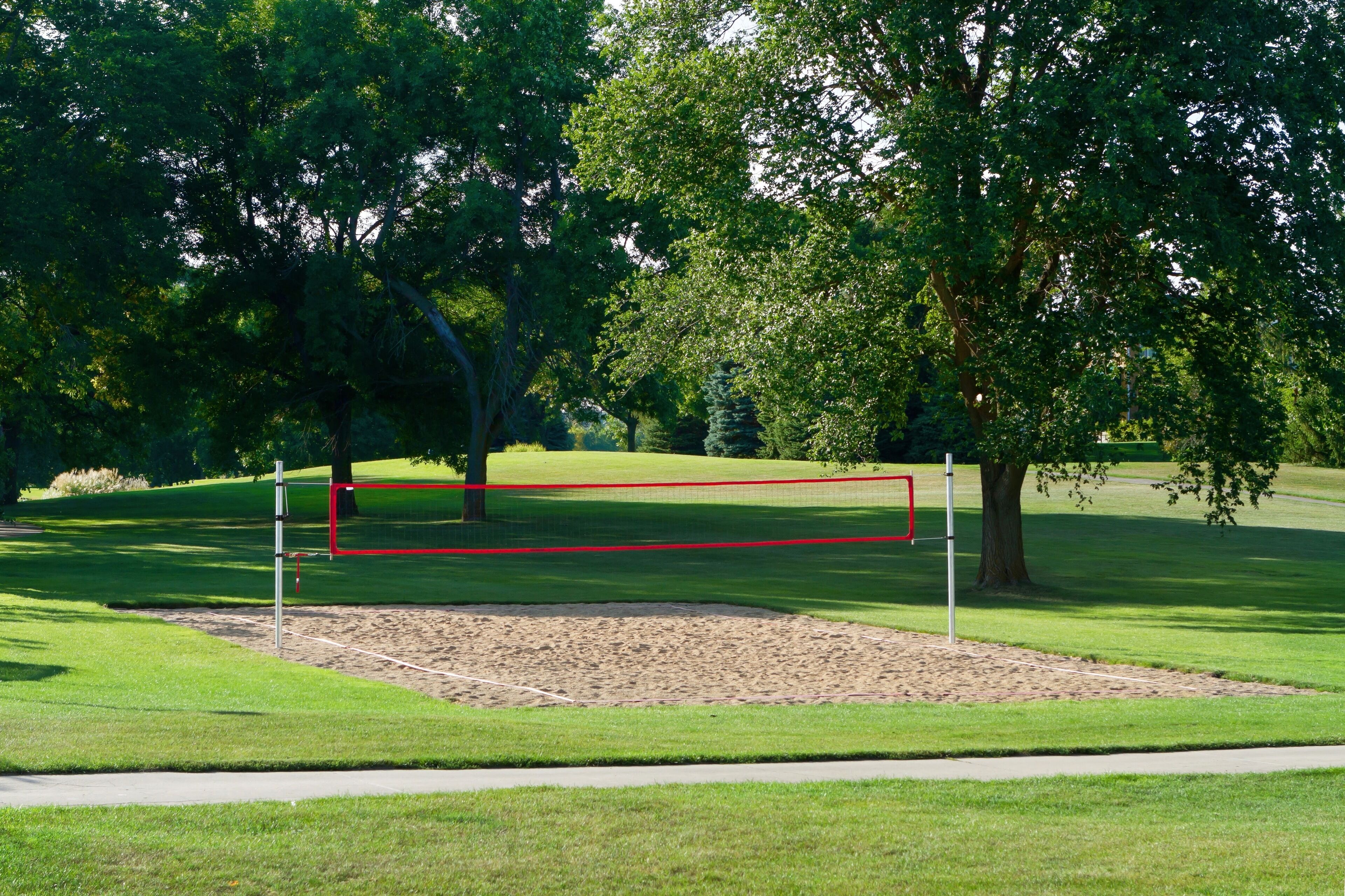 Golfkenttä, jossa on hiekkabunkkeri, puita ja kirkas taivas.