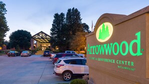 A sign for Arrowwood Resort & Conference Center by ClubHouse, featuring a modern building and a parking lot with several cars. - Lake Okoboji Resort & Conference Center (Okoboji)