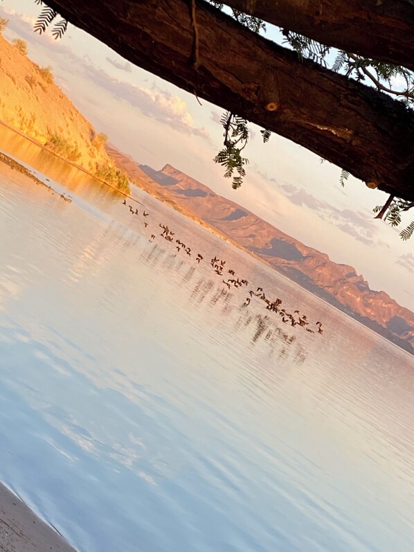 A calm lake with mountains in the background and a wooden structure in the foreground.