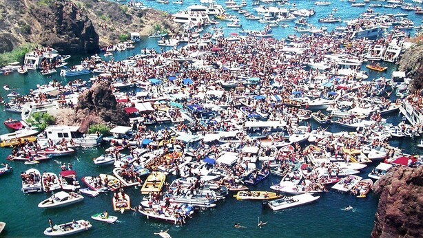 A crowded marina with numerous boats docked and people gathered on the shore. - Island Suites (Lake Havasu City)