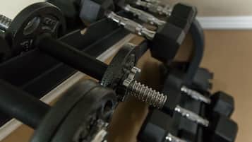 A rack of black dumbbells with adjustable weights.
