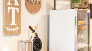 A kitchen counter with a coffee machine, a refrigerator, and decorative signs on the wall.