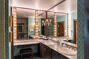 A bathroom with three sinks, a vanity, and a large mirror with lights. - Arizona Charlie's Decatur (Las Vegas)