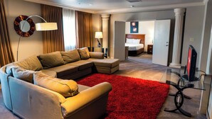 Una moderna camera d'albergo con un divano componibile, una moquette rossa, una televisione a schermo piatto e un letto sullo sfondo.