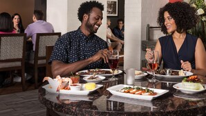 Un ristorante con un tavolo rotondo apparecchiato per due, con piatti di pesce, un dessert e bevande.