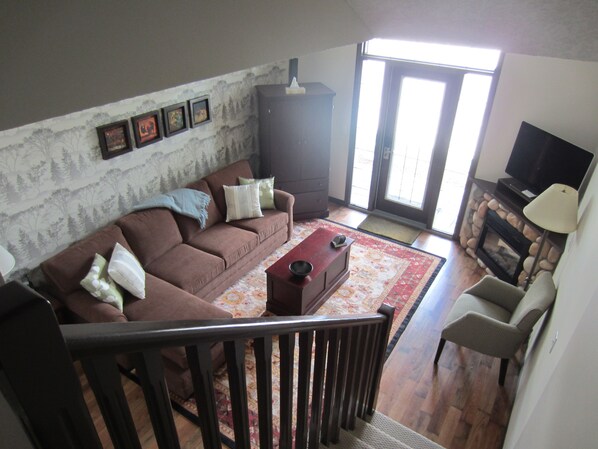A living room with a brown sofa, a coffee table, a fireplace, and a television.