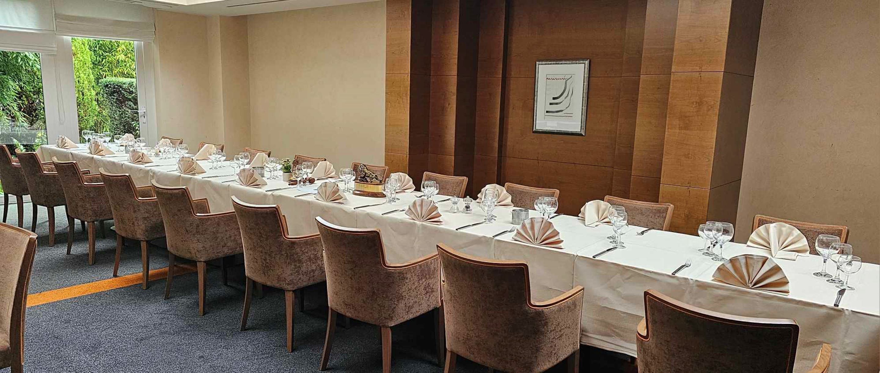 A long dining table set for a formal event with chairs and table settings.