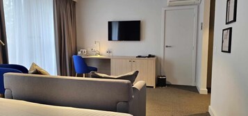 Una habitación de hotel con cama, escritorio, silla, televisor y puerta.