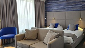A hotel room with a large bed, two bedside tables, a sofa, and a chair. - Hotel Les 3 Clés (Gembloux)