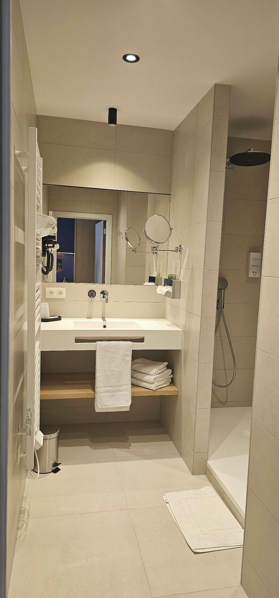 A modern bathroom with a sink, mirror, and shower.