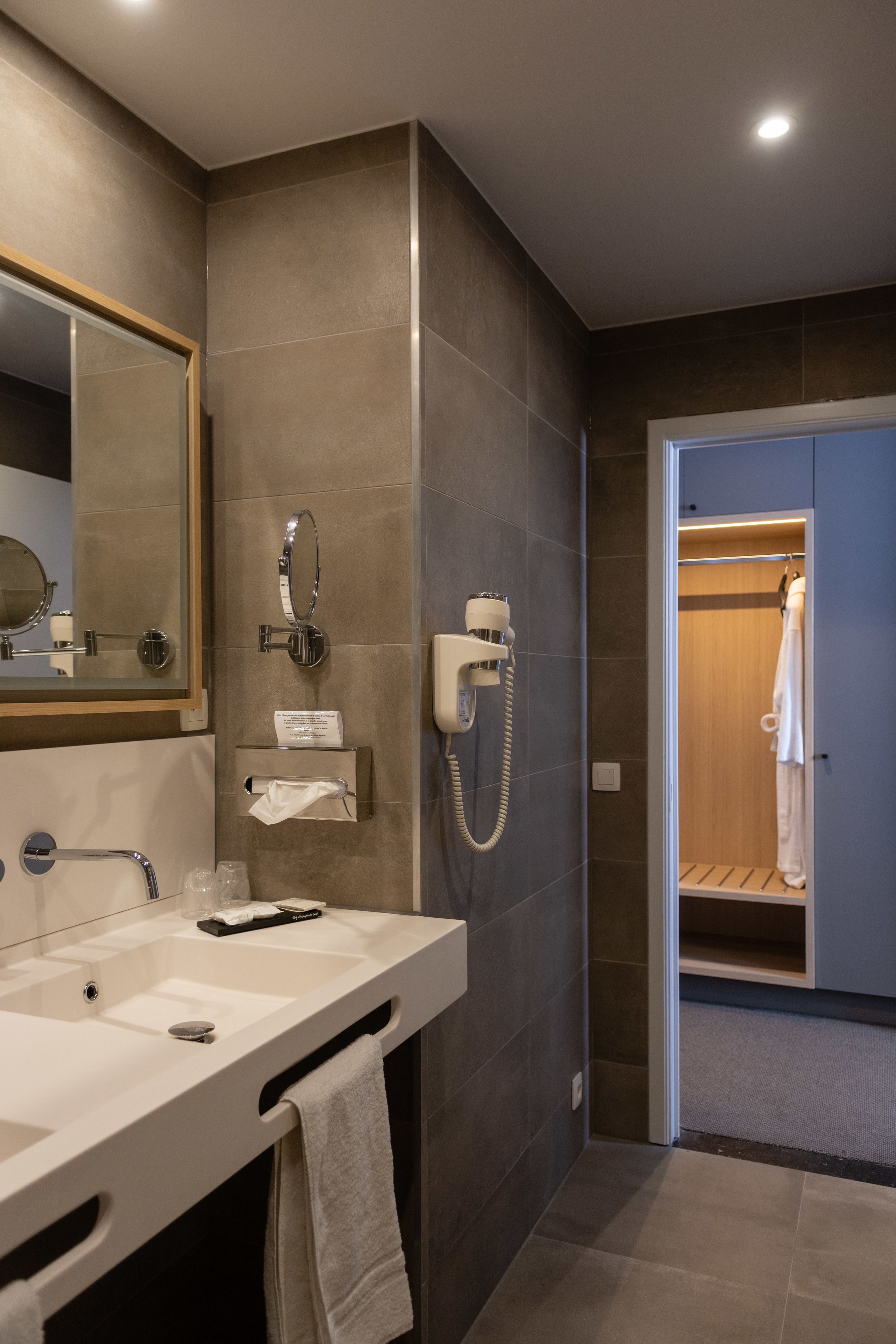 A modern bathroom with a large mirror, a sink, and a shower area.