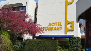 A hotel with a prominent yellow key-shaped sign. - Hotel Les 3 Clés (Gembloux)