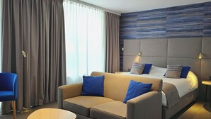 A hotel room with a large bed, a sofa, a small table, and a chair. - Hotel Les 3 Clés (Gembloux)