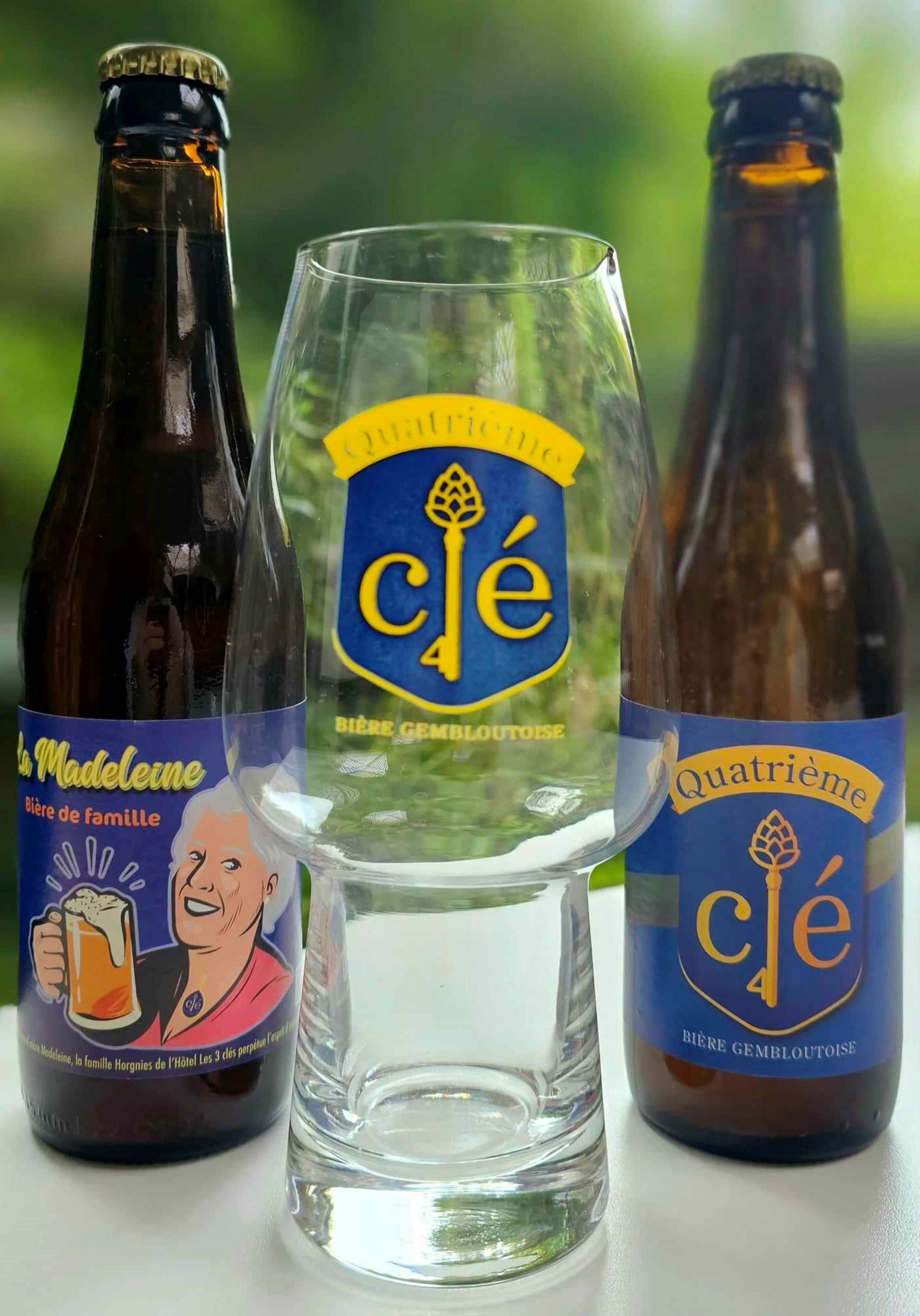 Three bottles of 'Clé' beer and a clear glass in the center.