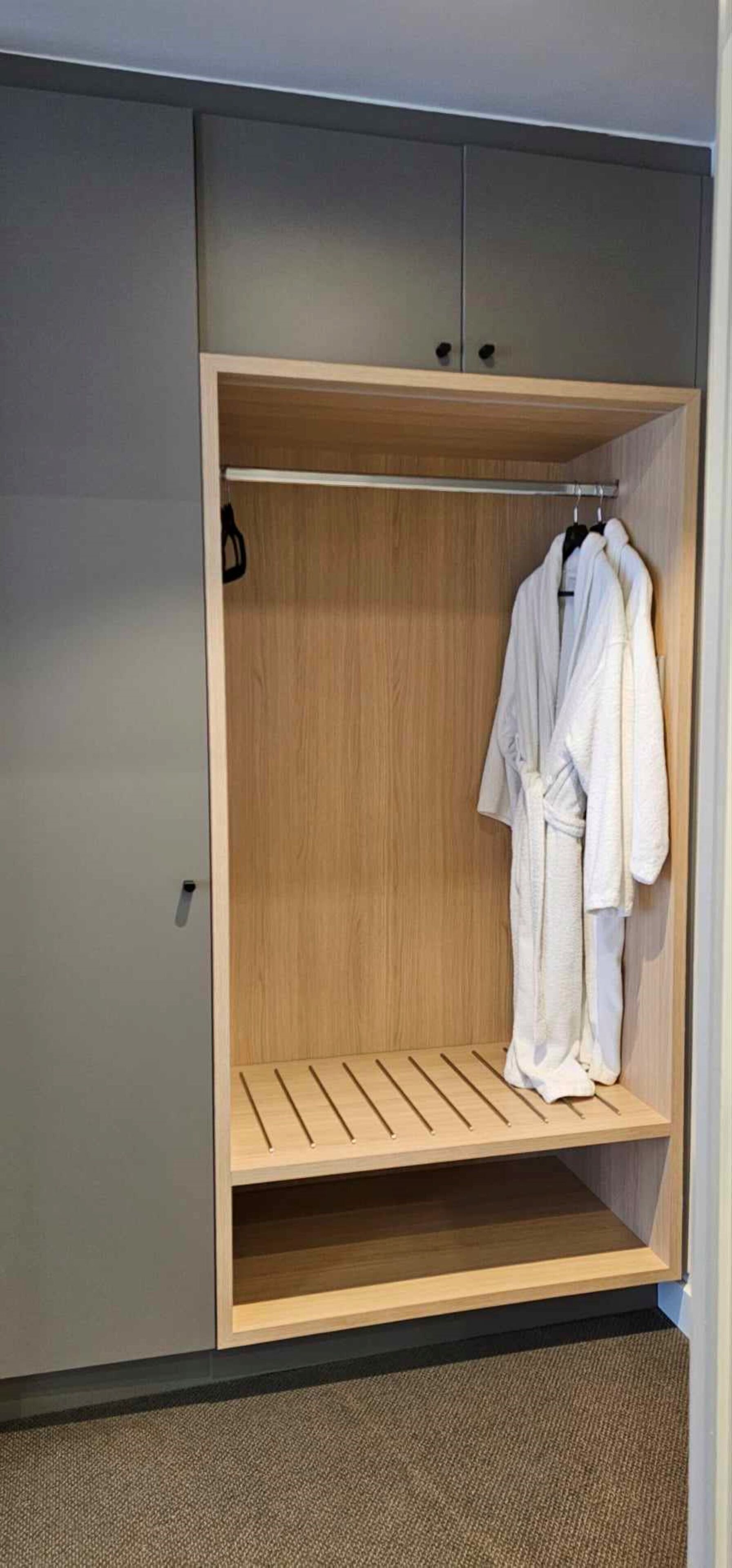 Un dressing avec une étagère en bois et un porte-manteau.